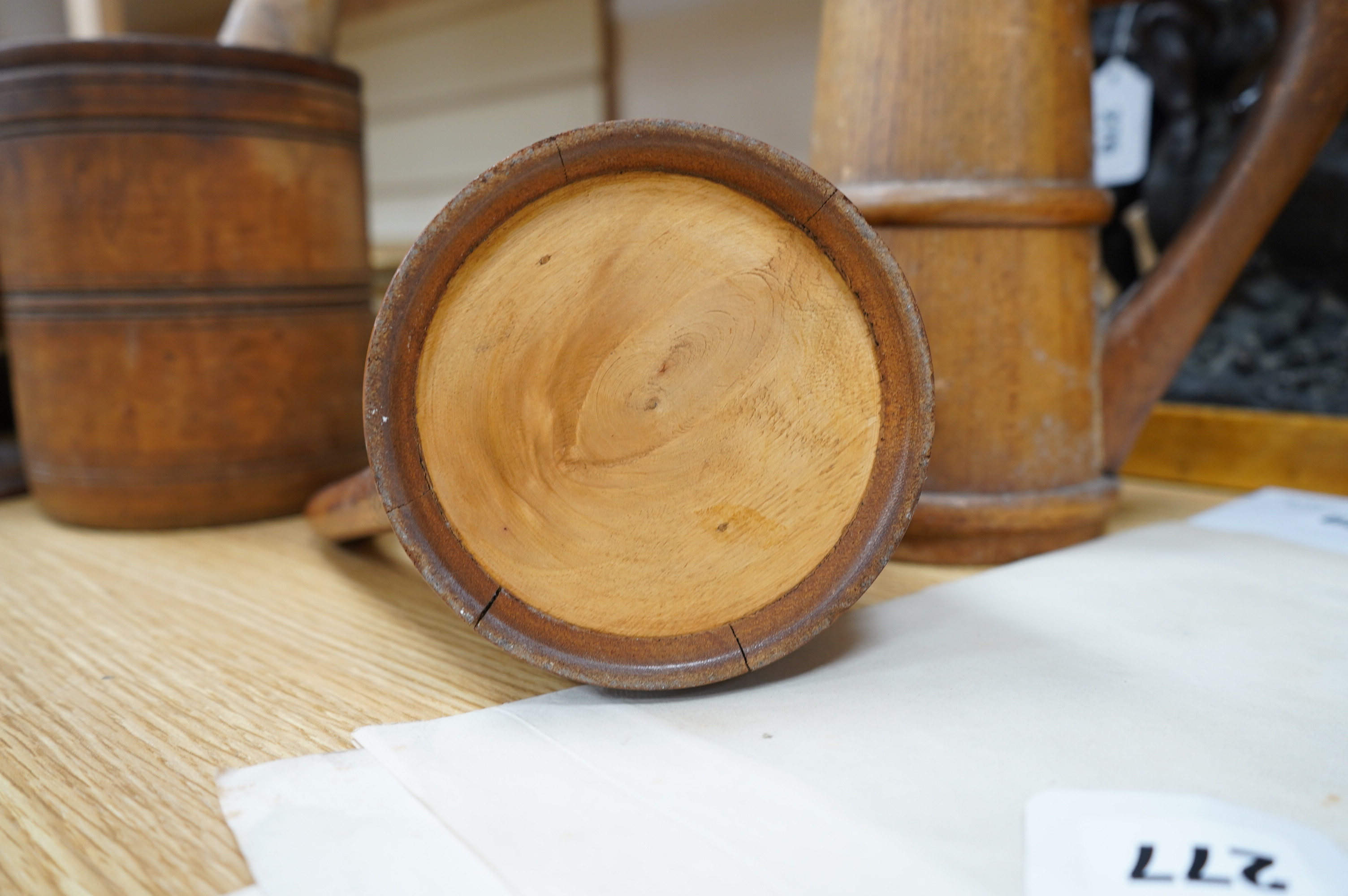 A pair of staved beech flagons, 23cm high, a wooden pestle and mortar, 17.5cm, and turned wood lidded bowl, 18cm (5). Condition - fair